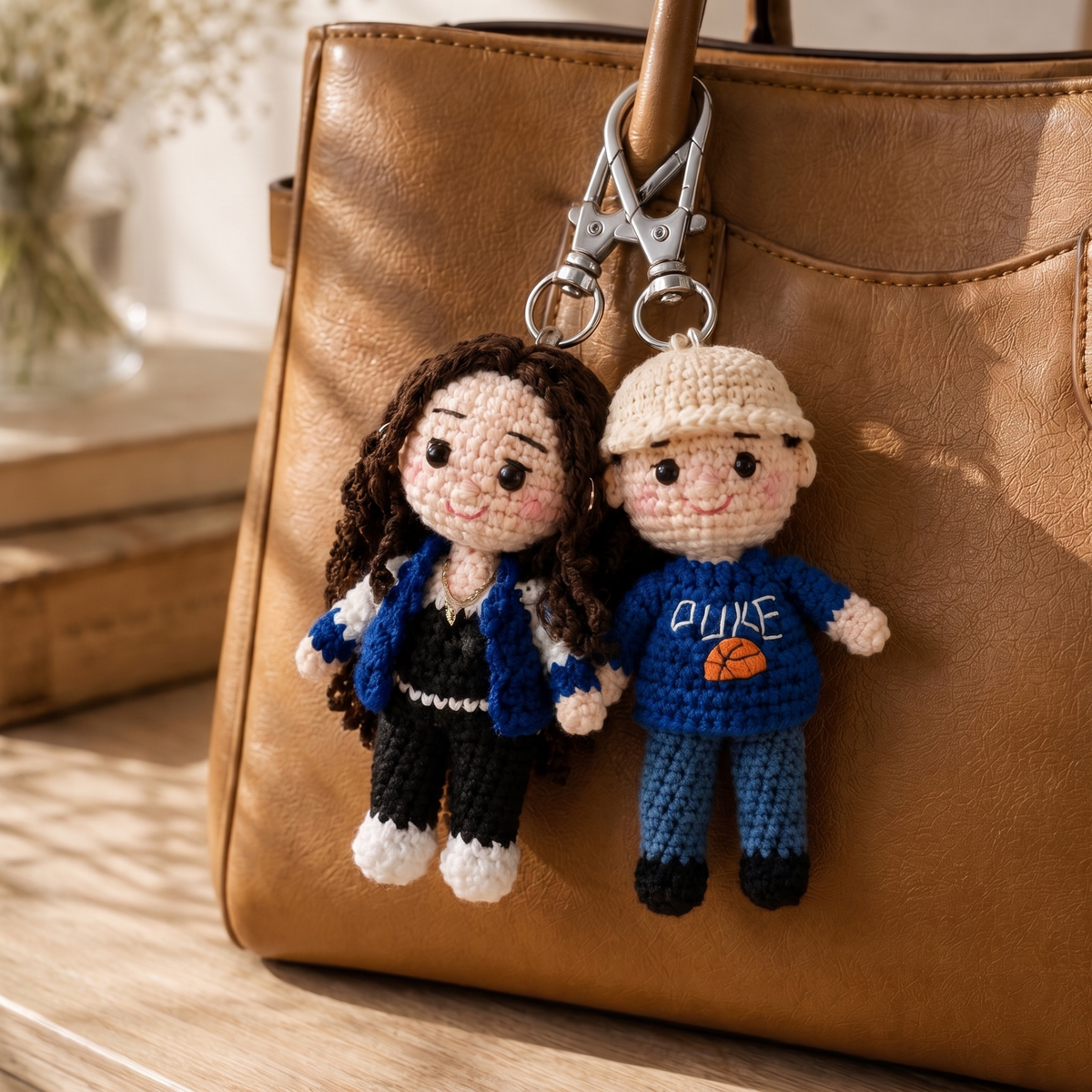 The same couple as two hand-crocheted charms side by side on a leather handbag